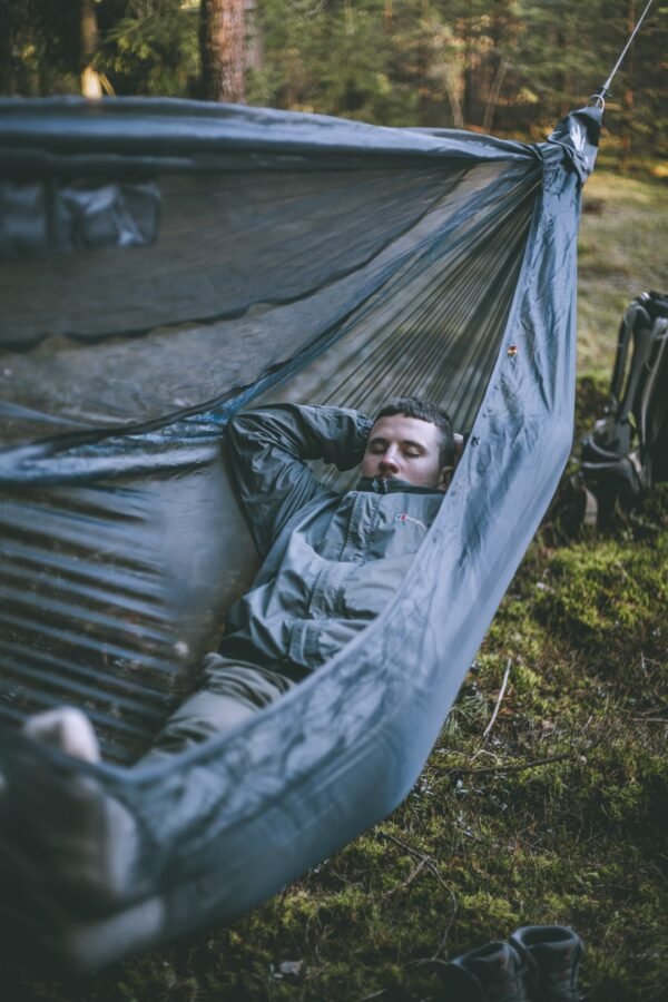 man lying in an ultralight hammock in the forest