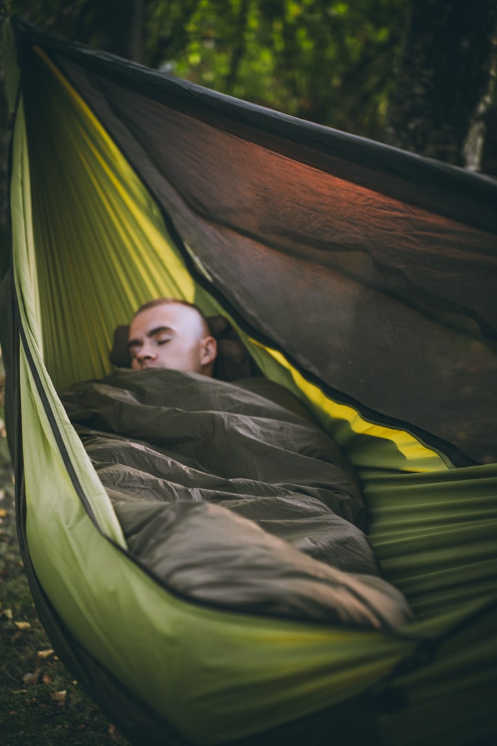 man lying in need.for.trees production hammock, with nft quilt, lying diagonally in hammock