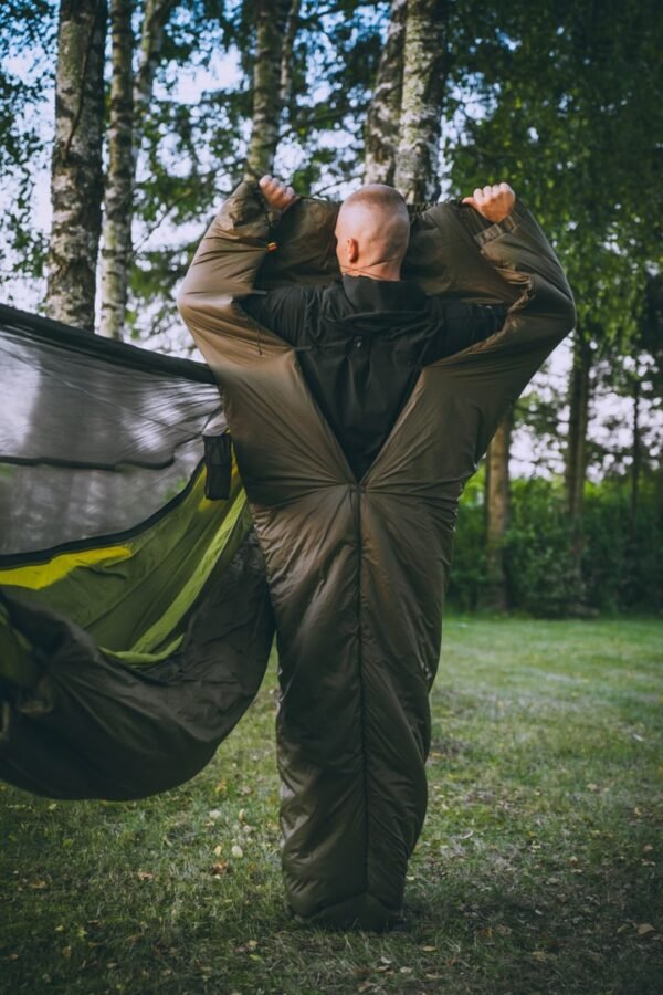 A person wearing a sleeping bag made by Needfortrees and standing up to show what it looks like when placed on the body